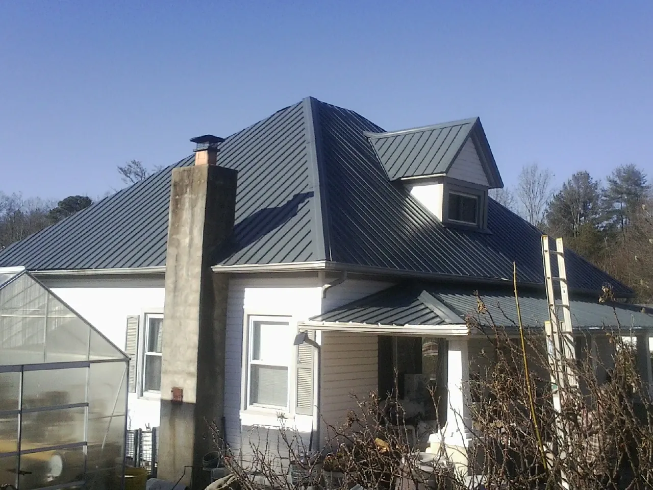 Dark blue standing seam metal roof on a white farmhouse with dormer — Slate & Tile Roof Repair by Roofing Brothers in Belfast