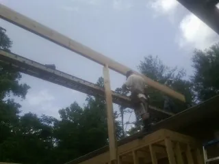 Carpenter setting a ridge beam over a new addition frame — Ice Dam Removal by Roofing Brothers in Belfast