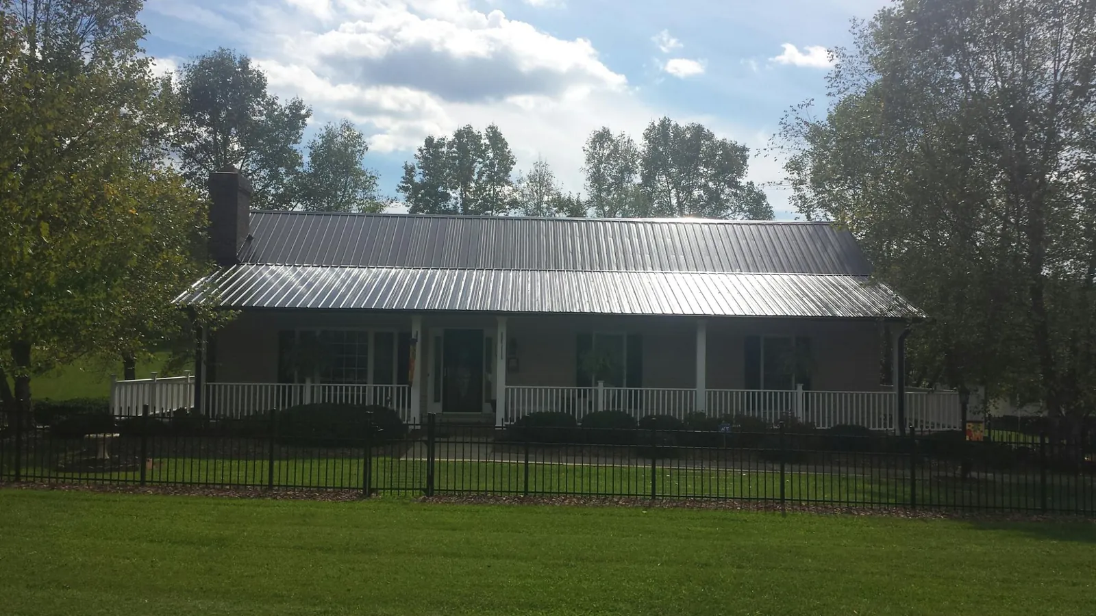Gray metal roof on a brick ranch with a full width front porch — Gutter Guard Installation work by our crew in Belfast